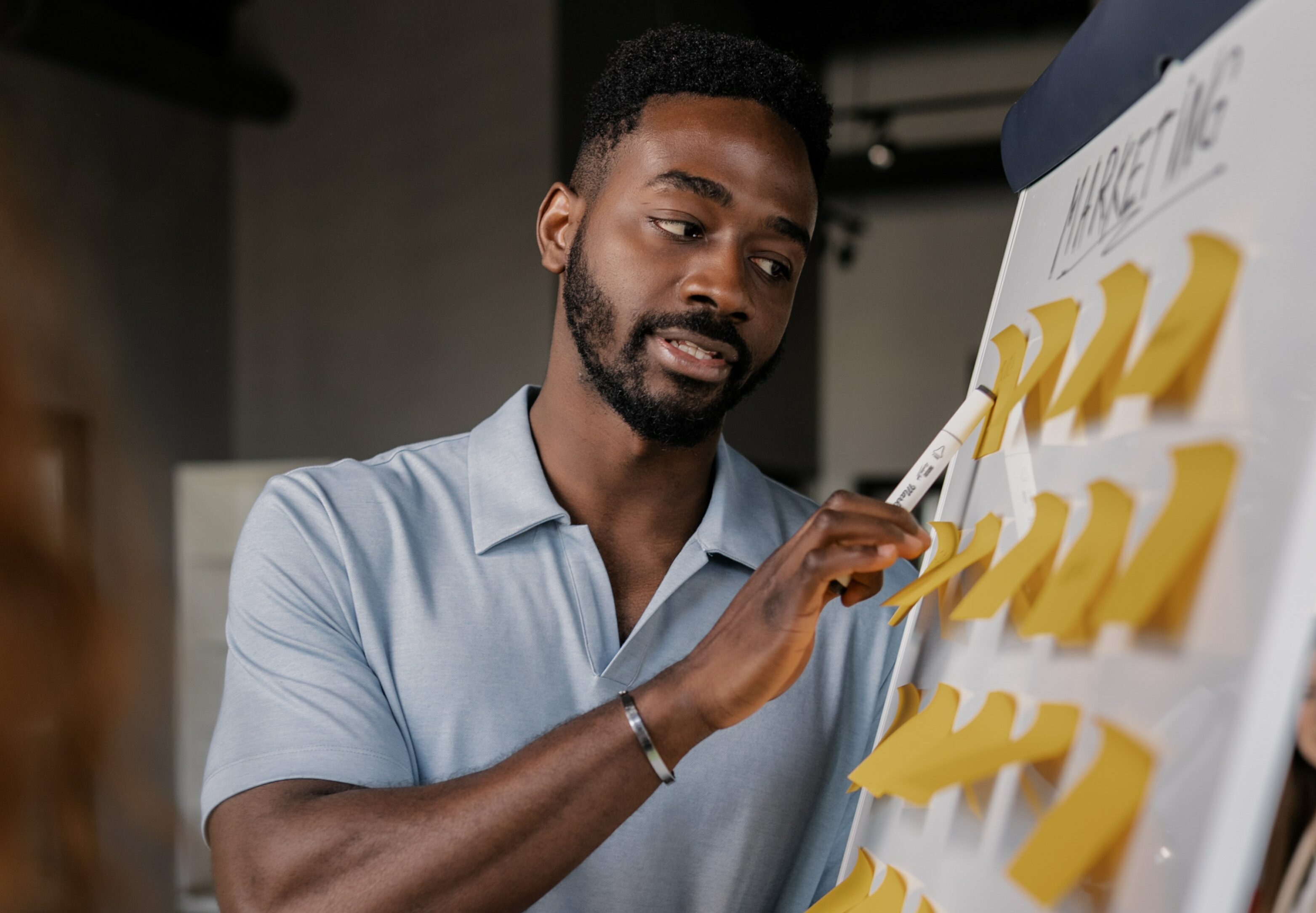 A man sticks post-it notes to a white board to understand his business marketing strategy