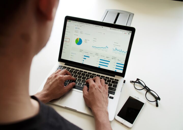 Typing on a laptop with pie charts and graphs on screen