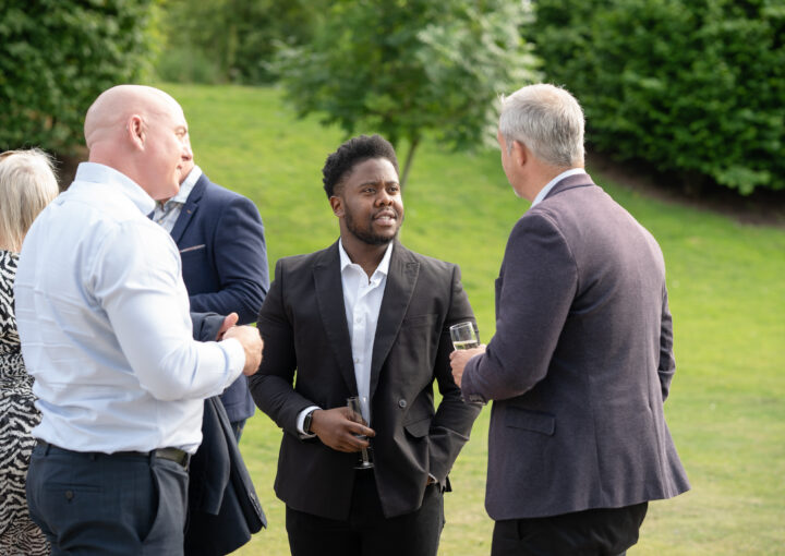 Three men in suits networking with champagne