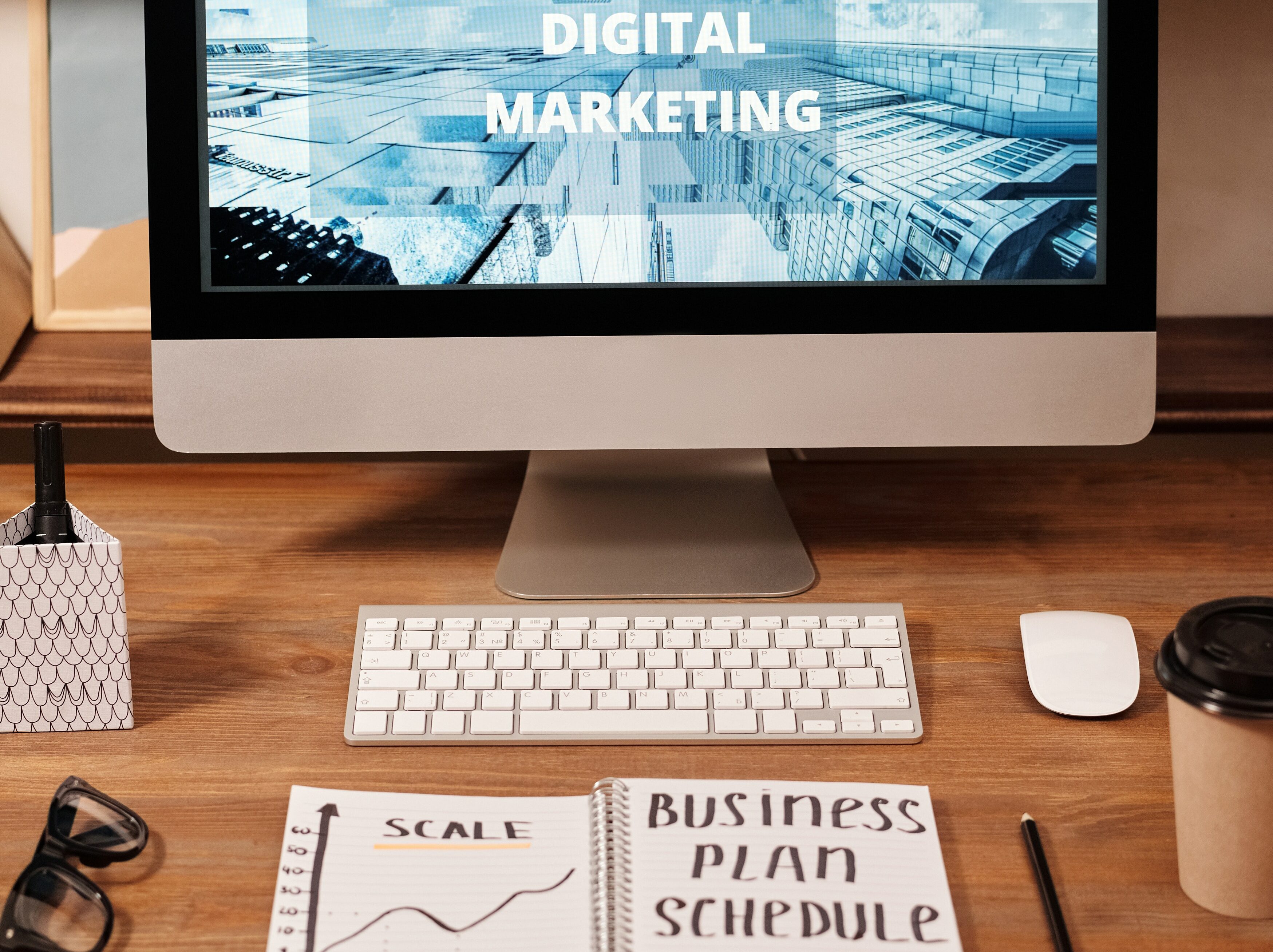 Turn your passion into profit. A Mac screen displaying the text 'Digital Marketing' and a notepad with 'Business Plan' written on it,