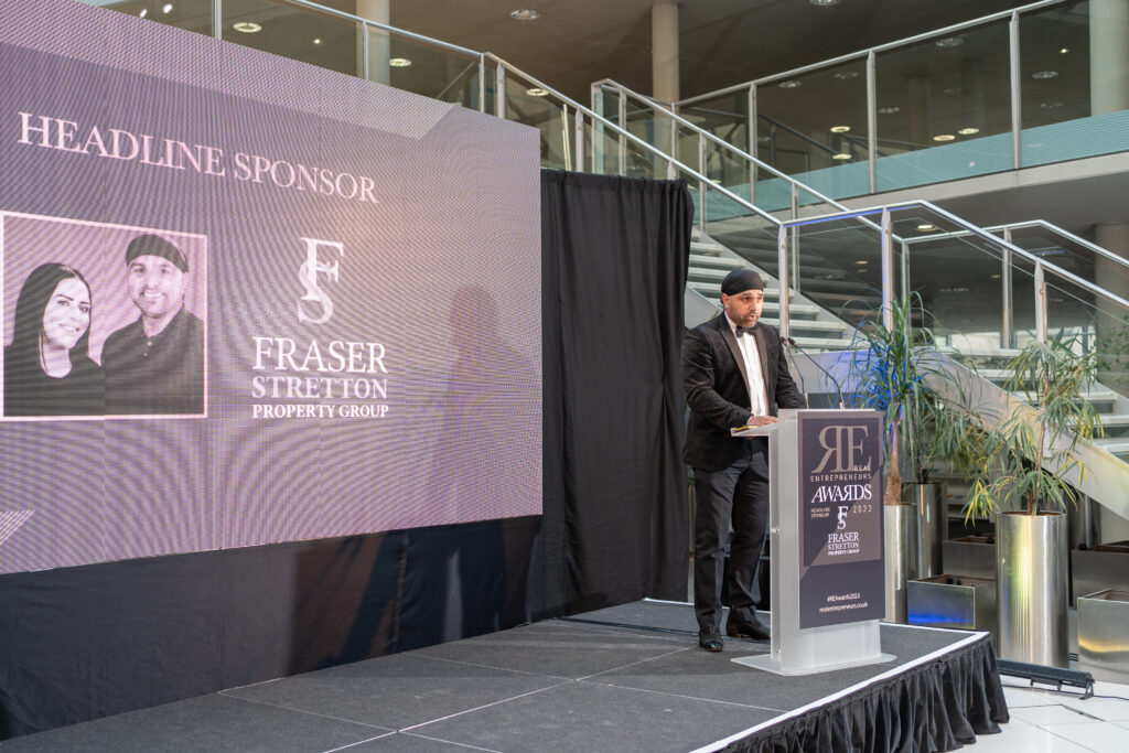 A sponsor and speaker stands on the podium at a business event