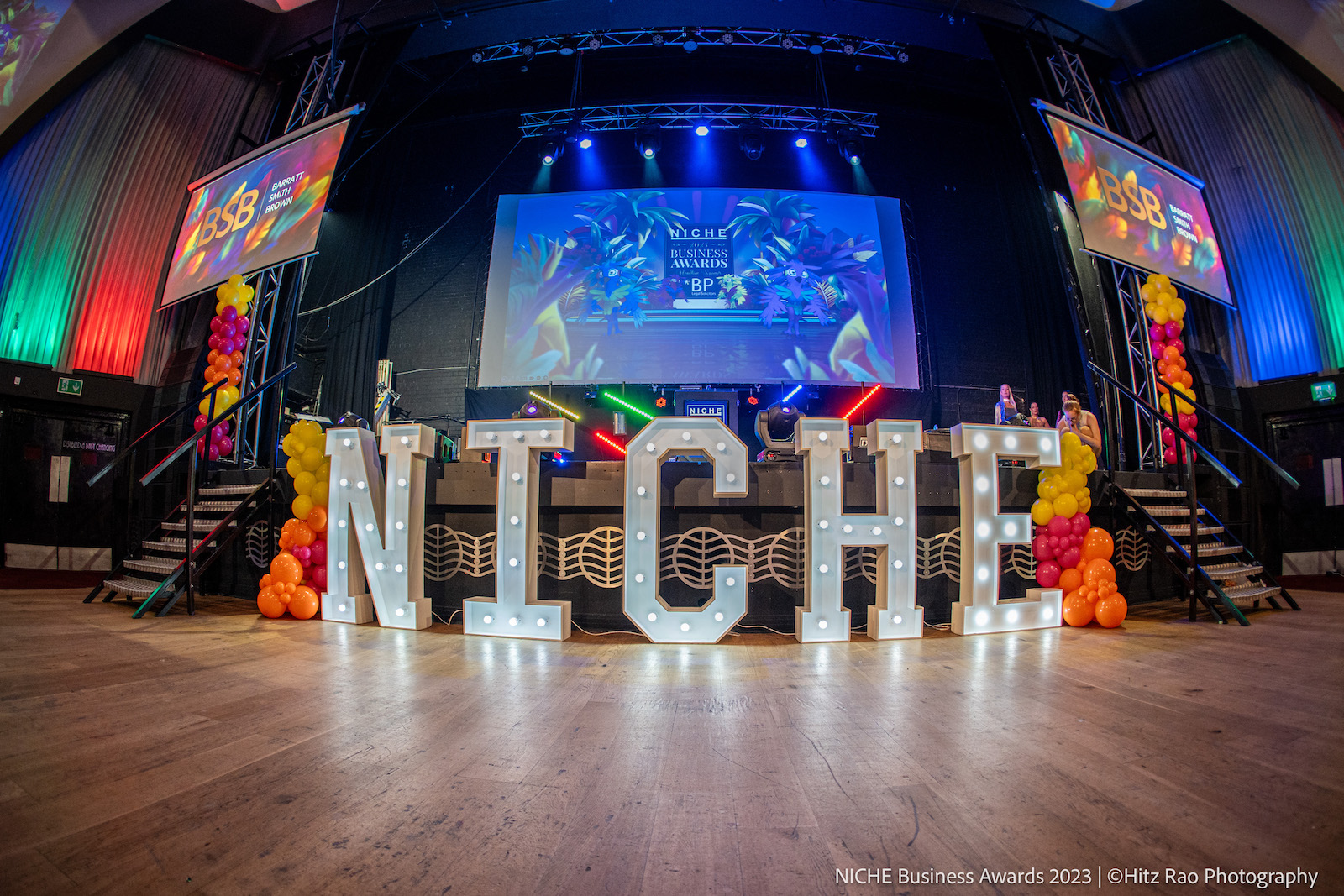 A huge light up sign saying NICHE in front of an awards ceremony stage coloured in red green and blue lights