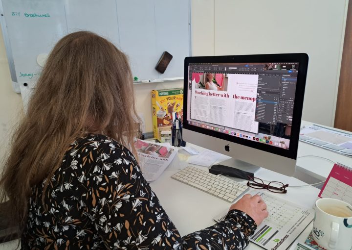 a female designer works on a Mac on InDesign creating a magazine article