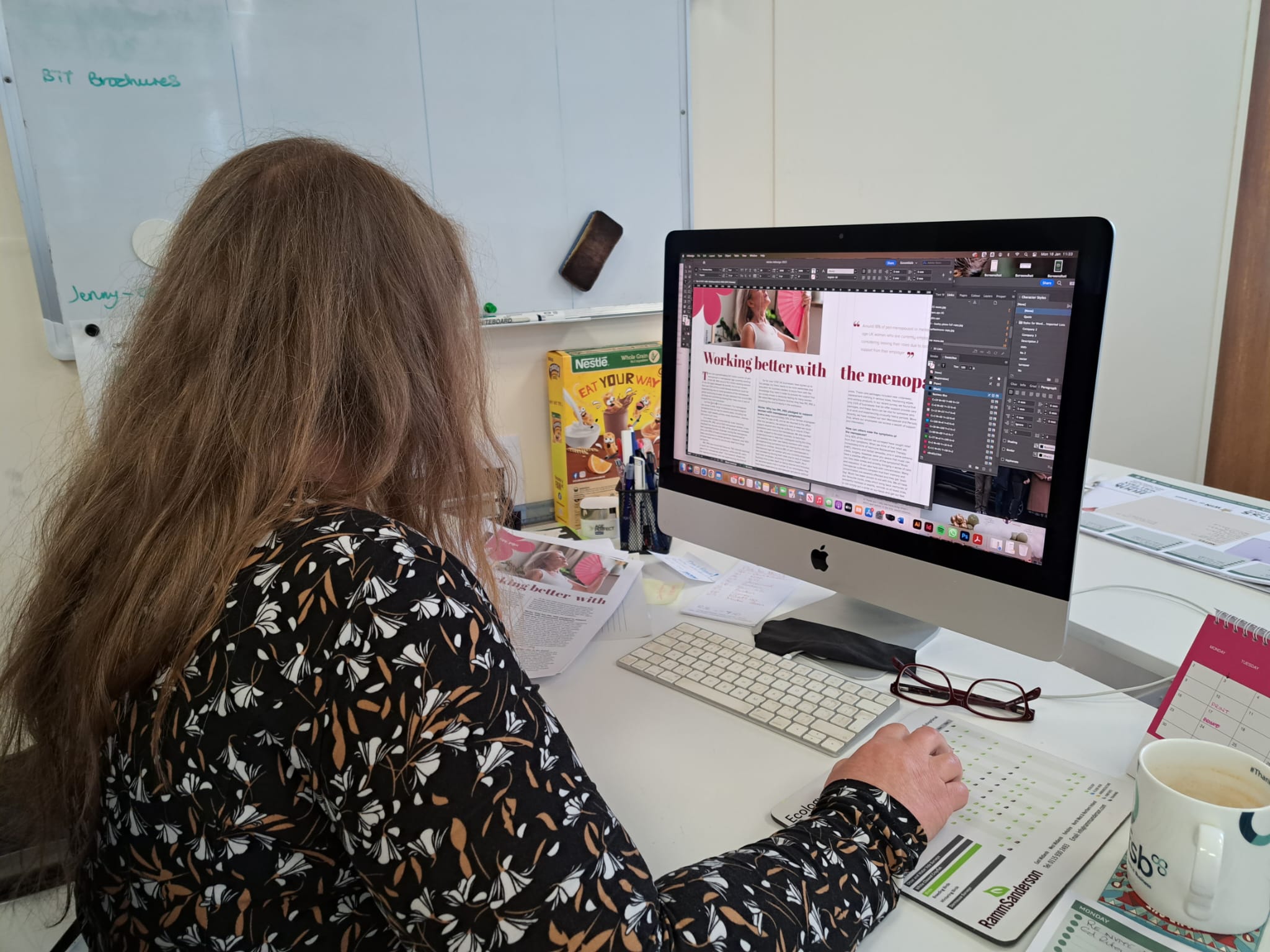 a female designer works on a Mac on InDesign creating a magazine article