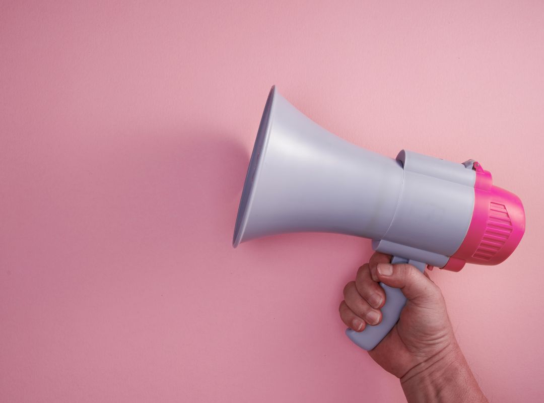 pink wall with a hand holding a megaphone